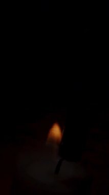 Dikey video. Bir Cadılar Bayramı Balkabağının İçindeki Mum 'un Yakın Çekimi, Mumları Yakmak ve Karanlıkta Gülümseyen ve Korkutucu Gözler. Dolly Kaydırıcı.