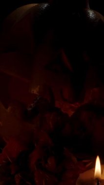 Dikey video. Küçük buruşuk bir balkabağını büyük bir Cadılar Bayramı balkabağından çıkarıp daha yakından göstermek. Kutlama için Karanlıkta Mumlar Sunağı.