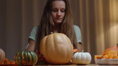 Konforlu bir evde Aile Gecesi, Cadılar Bayramı 'nda Yeni Oyulmuş Bir Fener Gösteren Bir Kadın. Masada Kabaklar.