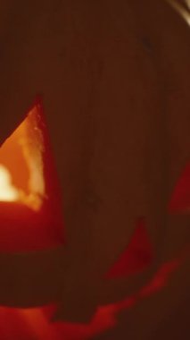 Dikey video. Cadılar Bayramı sona erer ve Jack-o 'Lantern' ın İçindeki Alevli Işık söner. Karanlık Oda 'da Yakın Çekim.