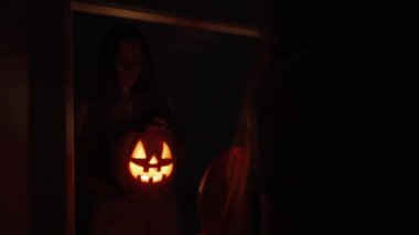 Karanlık Yatak Odası 'nda Aynanın Önündeki Kadın, Ilık Işık ve İçeriye Bakışlı Balkabağı Tutar, Lid' i Açar. Cadılar Bayramı Ritüeli kavramı.