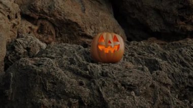 Kayalıklarda, içinde ışık olan bir balkabağı Jack-O 'Lantern bana bakıyor..