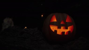 Cadılar Bayramı için balkabağı Jack-O 'Lantern Kayalıklardaki Karanlık Mağarada Yanan Işık ile. Uzakta mumlar, Azizler Günü için Statik Arkaplan.