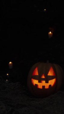 Dikey video. Sallanan Kamera Hareketleri Mağaranın İçindeki Kayalıklarda Yanan Mumlarla Jack-O 'Lantern' ı Yakıyor.