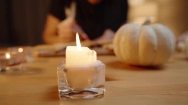 Cadılar Bayramı öncesi hazırlık, Masa 'da Aile Hazırlığı. Bir kadın zencefilli kurabiyeleri süslerken parmağındaki kremayı yalıyor..
