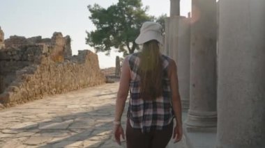 Antik Mimaride Gezinen, Büyük Sütunların yanında yürüyen, Çevresindeki Tarihi kucaklayan bir kadın.