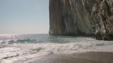 Görkemli Uçurum Parıldayan Deniz 'e bakıyor Dalgalar yavaşça Rocky Shoreline çarpıyor, Güneşin Ilık Işığında Banyo yapıyor.