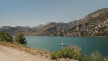 Etrafı Görkemli Dağlarla çevrili Sükunet Gölü, Tekneler yavaşça yüzüyor, Yol Tarafından Yavaş Çekimde Çekiliyor.