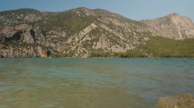 Berrak Turkuaz Suları ile Serene Gölü, Arkadaki Görkemli Dağ Sırası, Sakin ve Resimli Arkaplan Oluşturur.