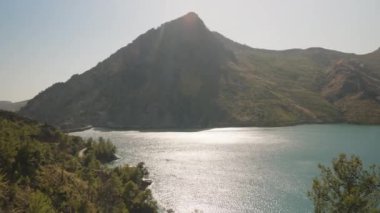 Güneş Işığı Turkuaz Gölü 'nden yansıyor. Kamera Görkemli Dağ' dan geçerken, Sakin Güzelliği ve Geniş Manzarayı Yavaş Çekimde Yakalıyor..