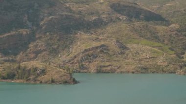 Turkuaz Gölü Dik, Verdant Tepeleri Arasında, Suyun Üzerinde Süzülen Bir Tekne, Engebeli ve Huzurlu Manzarayı Vurguluyor. Pano