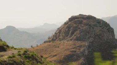 Rocky Hill Rolling Dağları 'nın Arkaplanına Karşı Belirgin Duruyor, Engebeli ve Görkemli Manzarayı Vurguluyor. Otomobil Penceresinden Göster