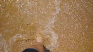 Sahil şeridi boyunca yürümek, Islak Kumda Güneşin Işıltılı Yansımasını Yakalayacak Bir Ayak Adımları.