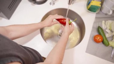 Lavaboda kırmızı çan biberi yıkıyorum, yemek pişirmek için temiz olmasını sağlıyorum..