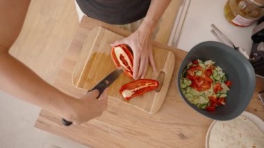 Tahta tahtada kırmızı çan biberi kesmek, Salataya canlı renk eklemek.