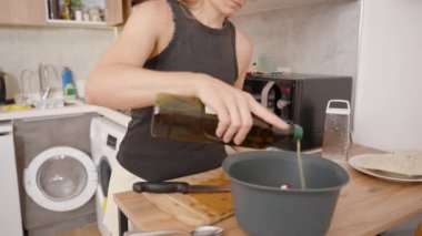 Genç kadın salataya zeytinyağı ekliyor, lezzetini zenginleştiriyor..