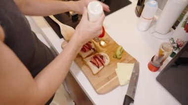 Sandviçin üzerine sos serpiştirmek, Lezzetli bir ısırık için hazırlamak.