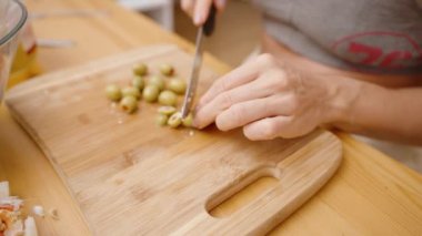 Yeşil zeytinleri mükemmel yarım dilimlemek, Taze salataya tuzlu bir ısırık eklemek.