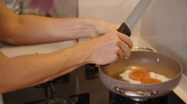 Tavaya yumurta kırmak, Sosis dilimlerinin yanında kızartmaya hazırlanmak..