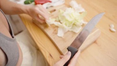 Taze salata malzemeleri hazırlanıyor, Çıtır Marul doğrarken dikkatlice elinde bıçak tutuyor..