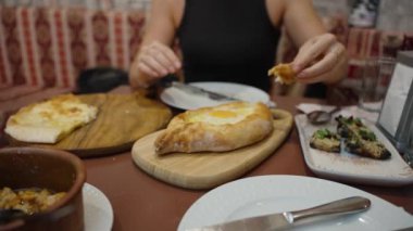 Sıcak Khachapuri 'den gelen hamuru yapışkan yumurta merkezine batırıyor. Bu Adjarian spesiyali zengin peynir ve ekmeği birleştirip karşı konulmaz bir lezzet deneyimi yaratıyor..