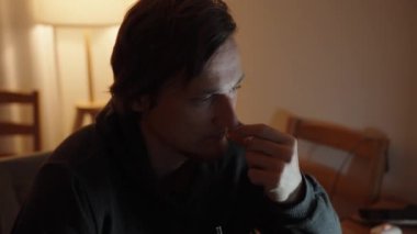 Düşünceli Munching, genç bir adam jelibonun tadını çıkarıyor. Sıcak ışık sıcak bir atmosfer yaratır..