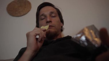 Düşünceli Crunch, bir adam dalgın dalgın bakarken cips yemekten hoşlanır. Rahatlatıcı ortam huzurlu ve içsel bir anın altını çiziyor..