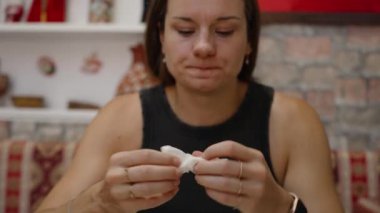 İçerik ve rahatlık içinde, genç bir kadın lezzetli bir yemekten sonra ağzını siliyor. Sıcak atmosfer ve lezzetli yemekler onu tatmin ediyor..