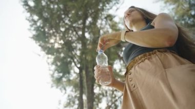 Su içen genç bir kadın ağaçların altında susuz kalır. Huzurlu ortam ana eklenir.