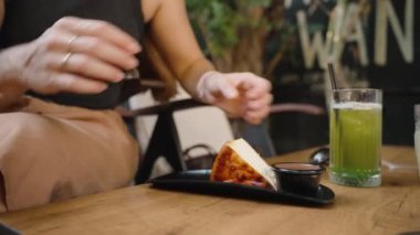 Tatlı servisi yapan genç bir kadın, bir dilim pastadan zevk almaya hazırlanıyor. Yeşil meyve suyu ona iyi gelir..