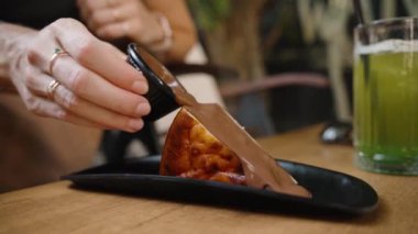 Çikolata koyan genç bir kadın, kekine zengin sos ekler. Kombinasyon bozulmuş ve lezzetli bir tatlı vadediyor..