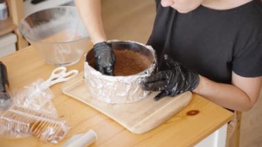 Pasta halkasına daha fazla kurabiye kırıntısı karışımı eklemek, Üssü eşitlemek demek. Sahne, Hazırlık Sürecinde İlgi ve Hassasiyeti Yansıtır.
