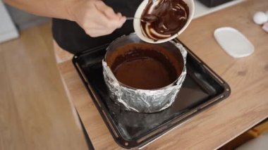 Erimiş çikolatayı hazır kabuğa dökerek, eşit dağıtımı sağlıyoruz. Zengin Çikolata Karışımı Cheesecake için Temel Katman.