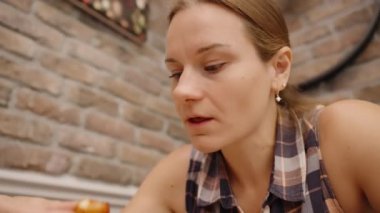 Isırık büyüklüğünde bir atıştırmalık elinde, Tuğla Duvarlı Kafe 'de İlgiyle İnceleniyor.