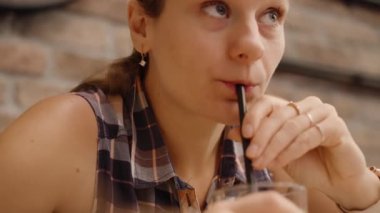 Kadın, siyah bir pipetle serinletici bir içecek yudumlar ve Charming Cafe 'de dinlenir..