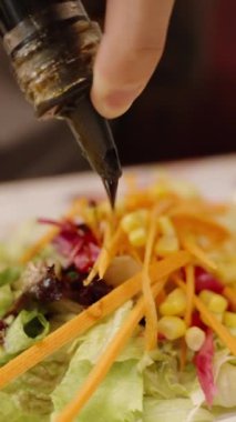 Dikey video. Taze salataya nar sosu ekliyorum, canlı sebze renkleri sergileniyor, eğlenmeye hazır..