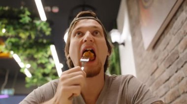 Adam çatallı kızarmış tavuğu ısırıyor, çağdaş bir kafede lezzetin tadını çıkarıyor..