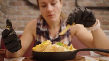 Siyah Eldivenli Kadın Peynirli Kızartma ve Çizburger yer, Samimi bir kafede yemeğinin tadını çıkarır..