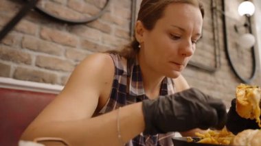 Siyah Eldivenli Kadın, Peynirli Isırıktan Zevk Alırken Rahatlatılmış Kafe Düzeninde Yemeğinin Tadını Çıkartıyor.