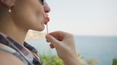 Lolipop Yiyen Kadın 'ın Yakın Çekimi Arkaplanda Güzel Bir Rıhtımla Zevk Almak.