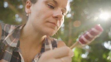 Kadın çizgili dondurmadan bir ısırık alıyor, günışığında lezzetin tadını çıkarıyor..