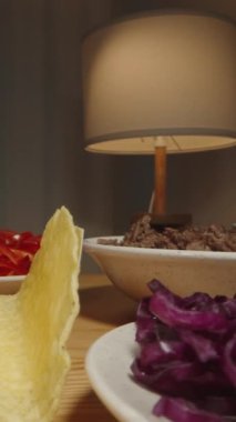 Dikey video. El, Taco Shell 'e domates sosu ekler. Masadaki çeşitli malzemelerle lezzetli bir yemek hazırlar. Dolly kaydırıcı, kapat..