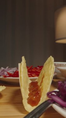 Dikey video. Dilimlenmiş tavuğu tako kabuğuna ekler ve lezzetli bir taco hazırlamaya başlar. Dolly kaydırıcı, kapat..