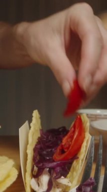 Dikey video. El, Taco 'ya Kirazlı Domates Dilimleri ekler, Lezzet ve Rengi Arttırır. Dolly kaydırıcı, kapat..