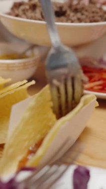 Dikey video. Kadın tako kabuğuna kıyma ekliyor, nefis bir ev yapımı taco hazırlıyor..