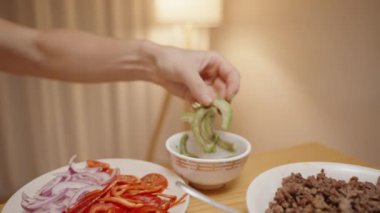 Kadın Taco Kabuğuna Avokado Dilimleri Ekliyor, Taze ve Lezzetli Taco Hazırlıyor.