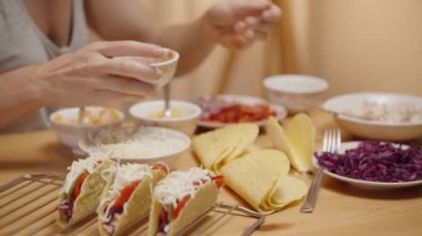 Kadın tako kabuğuna salsa ekliyor, ev yapımı tako için malzemeleri hazırlıyor..