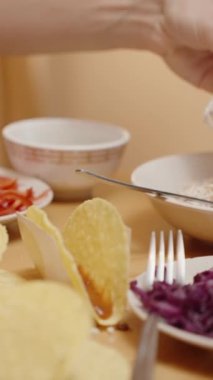 Dikey video. Kadın tako kabuğuna tavuk serpiştirir, Lezzetli bir dolgu yaratır.