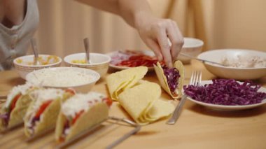 Kadın Taco Shell 'e Domates ve Kırmızı Lahana Ekliyor, Taze Malzemeler Anonim Şirketi.