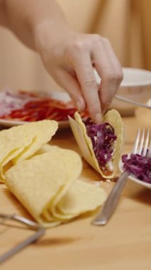 Dikey video. Kadın Taco Shell 'e Domates ve Kırmızı Lahana Ekliyor, Taze Malzemeler Anonim Şirketi.